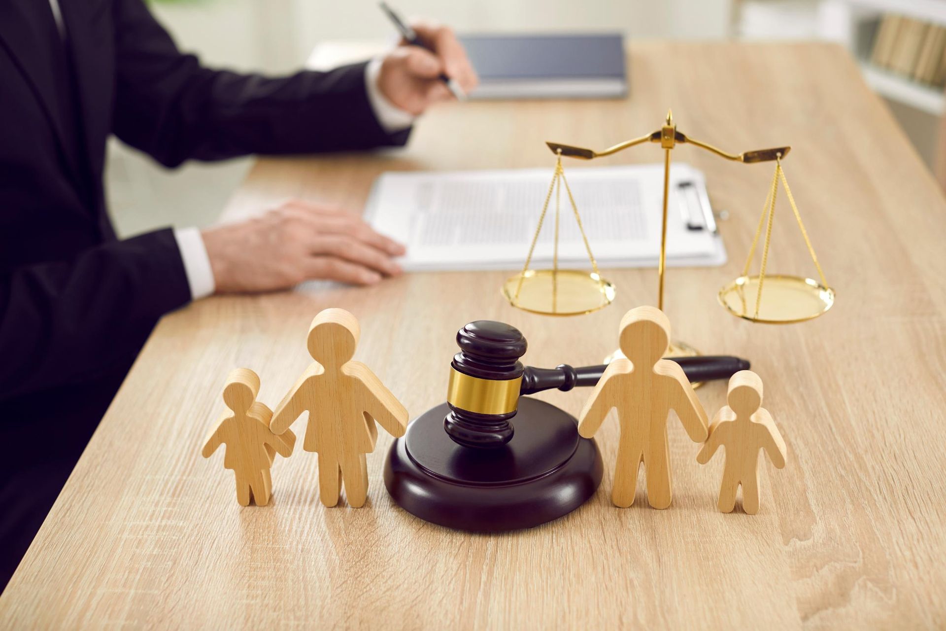 Lawyer’s desk with gavel, justice scales, and paper cutout family figures on a wooden table