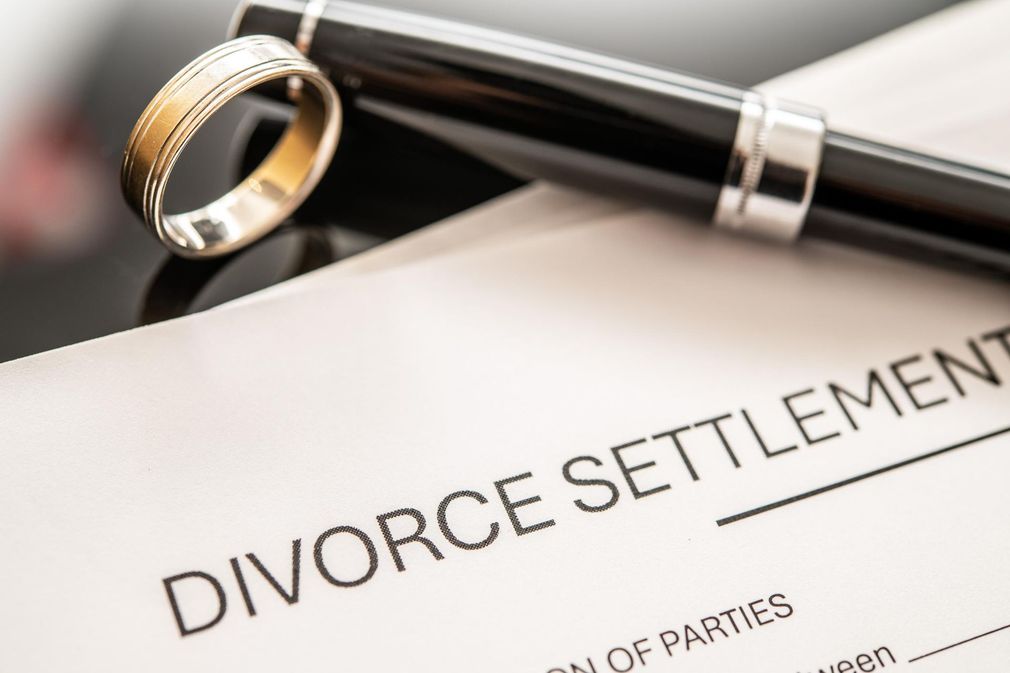 Divorce settlement document with a pen and wedding rings on top