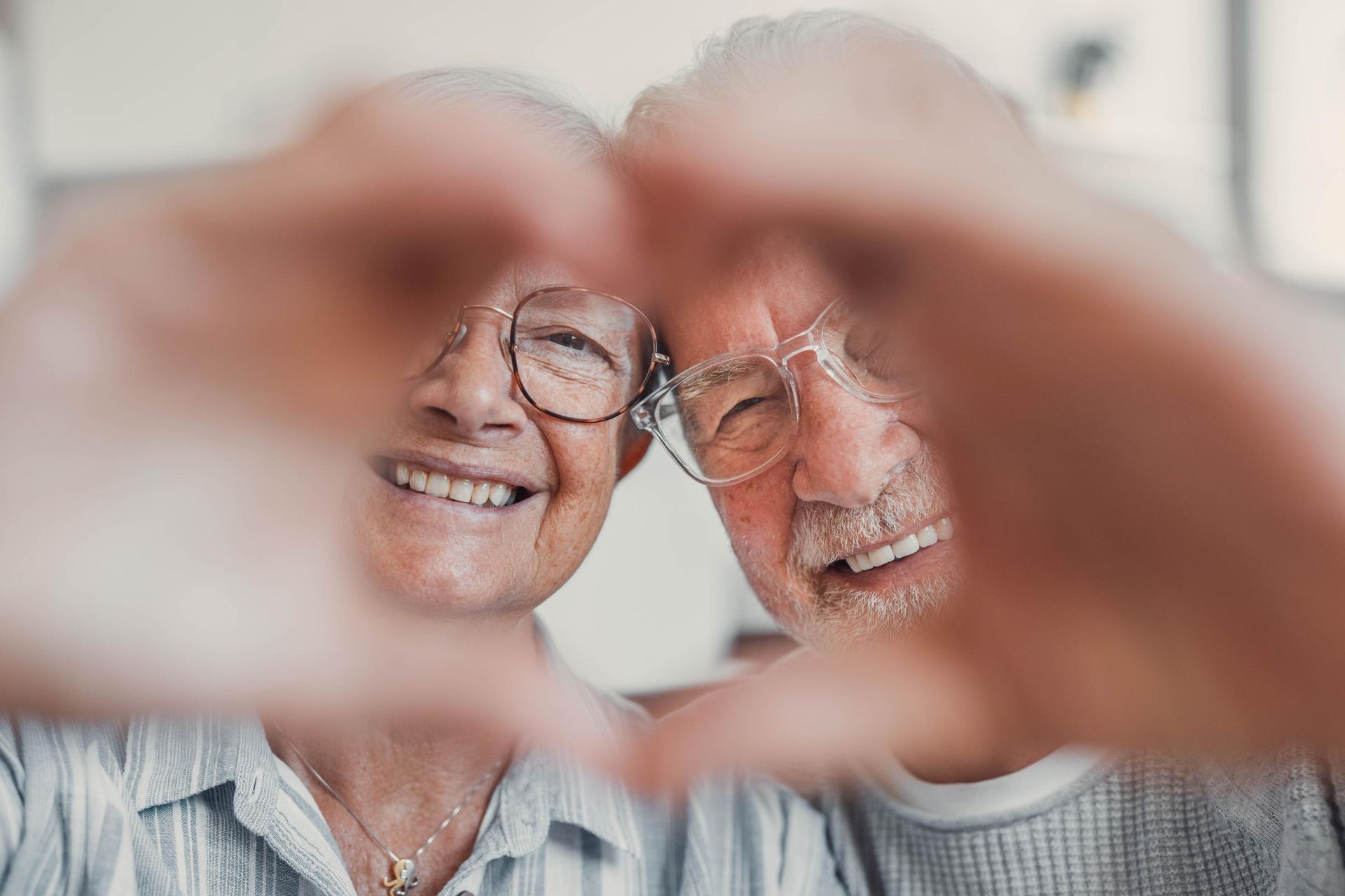 Two smiling people forming a heart shape with their hands in front of their faces