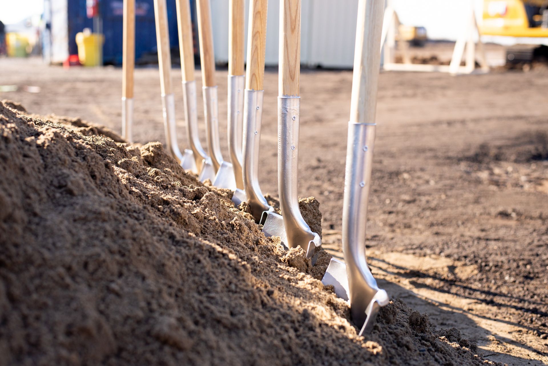 Shovels lined up in a dirt mound at a construction site Photography by Lume Creative