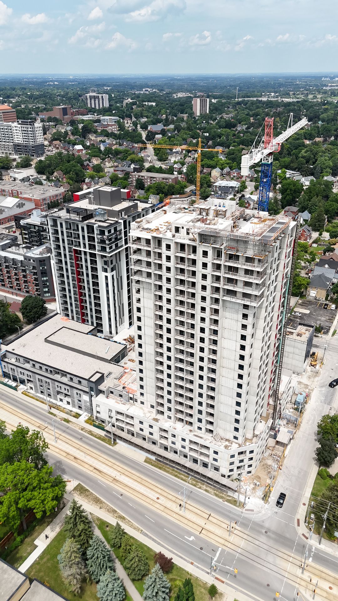 Aerial view of high-rise buildings under construction beside a wide road in a cityscape.