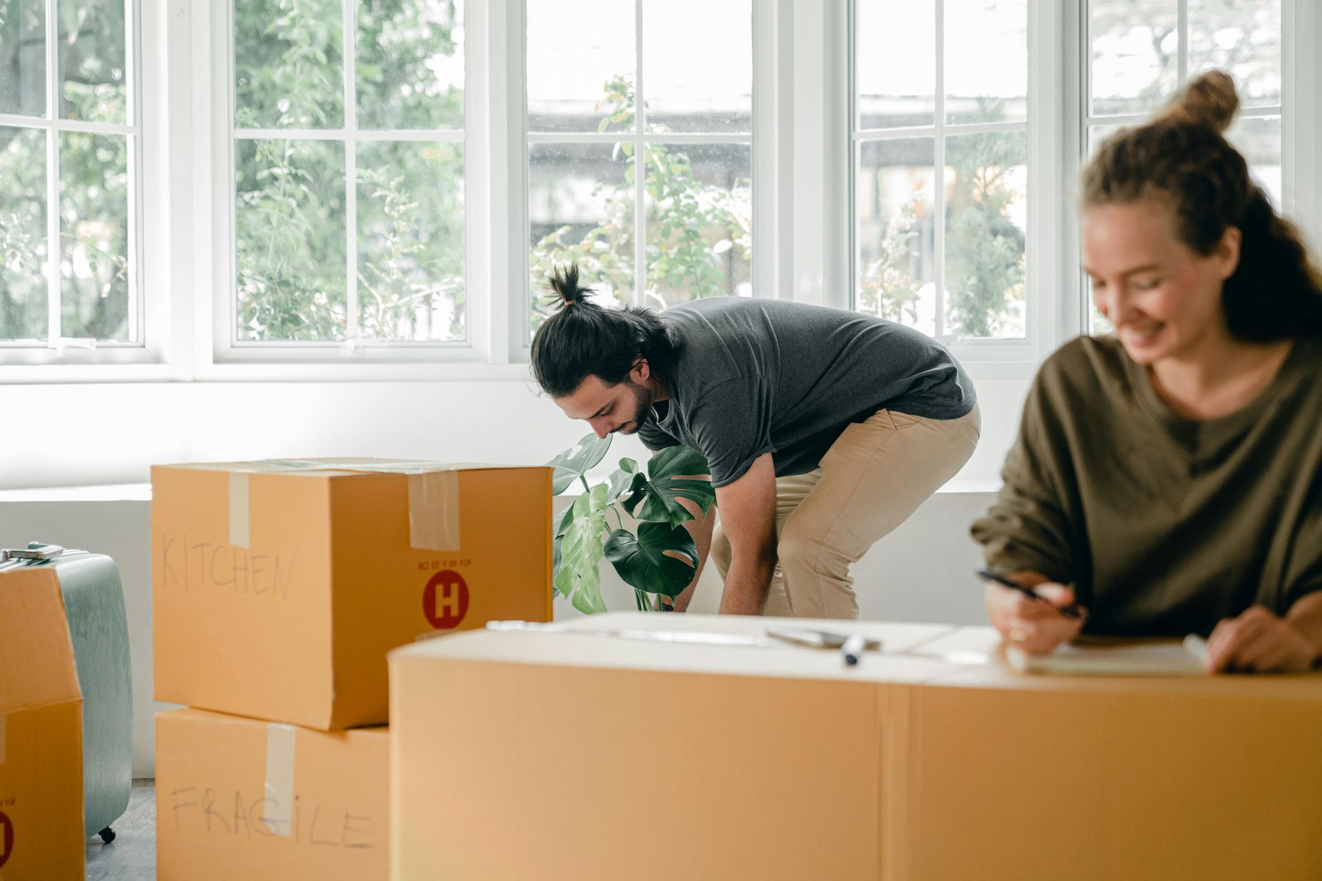A man and a woman are packing boxes in a living room.