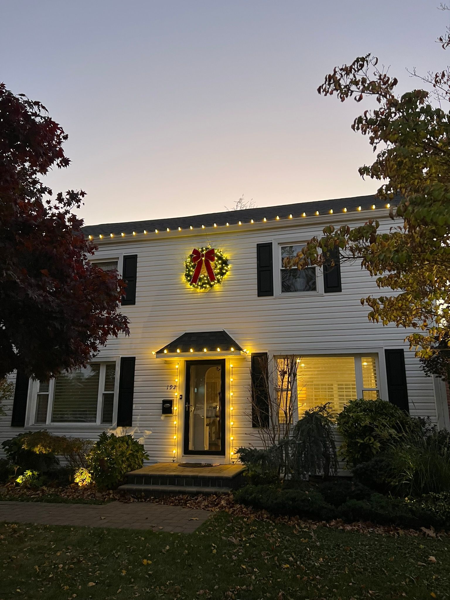 A house with christmas lights and a wreath on the front door
