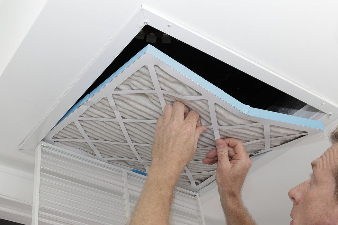 a person changing out an air filter at a customers home in surprise