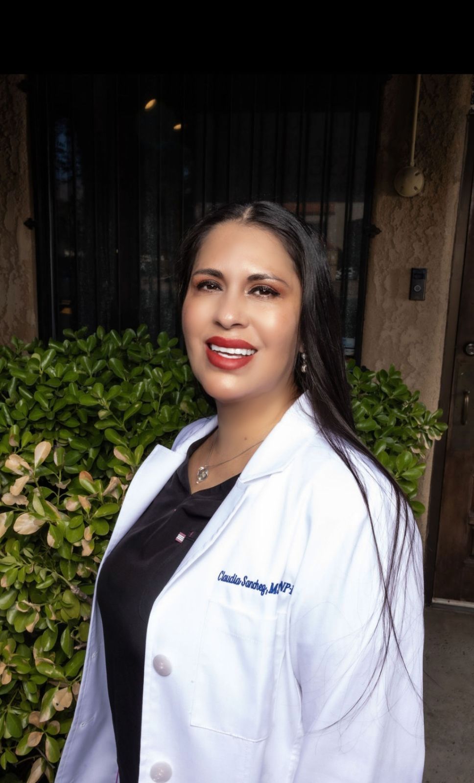 A woman in a white lab coat is smiling for the camera.