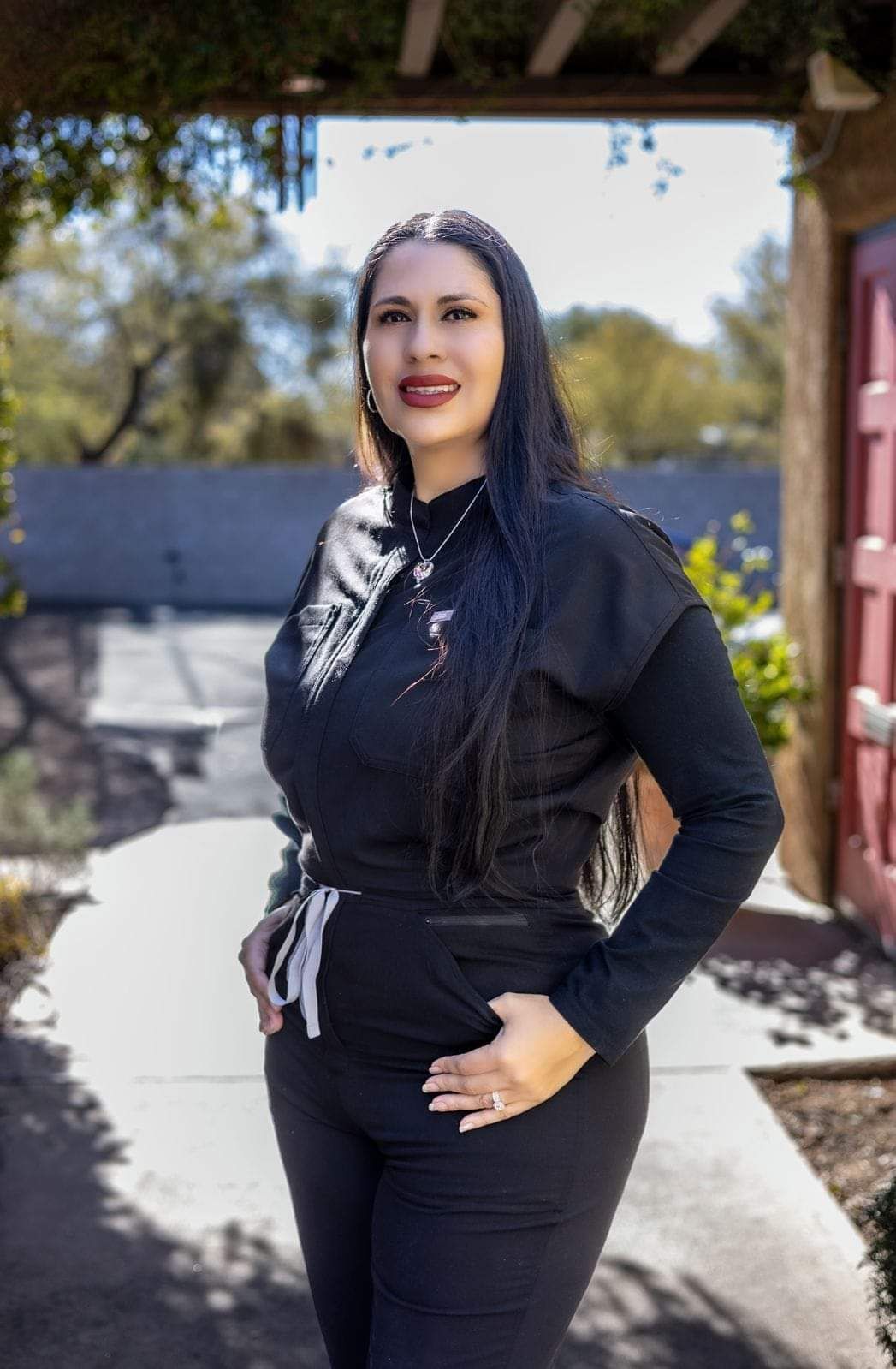 A woman in a black shirt and pants is standing on a sidewalk.