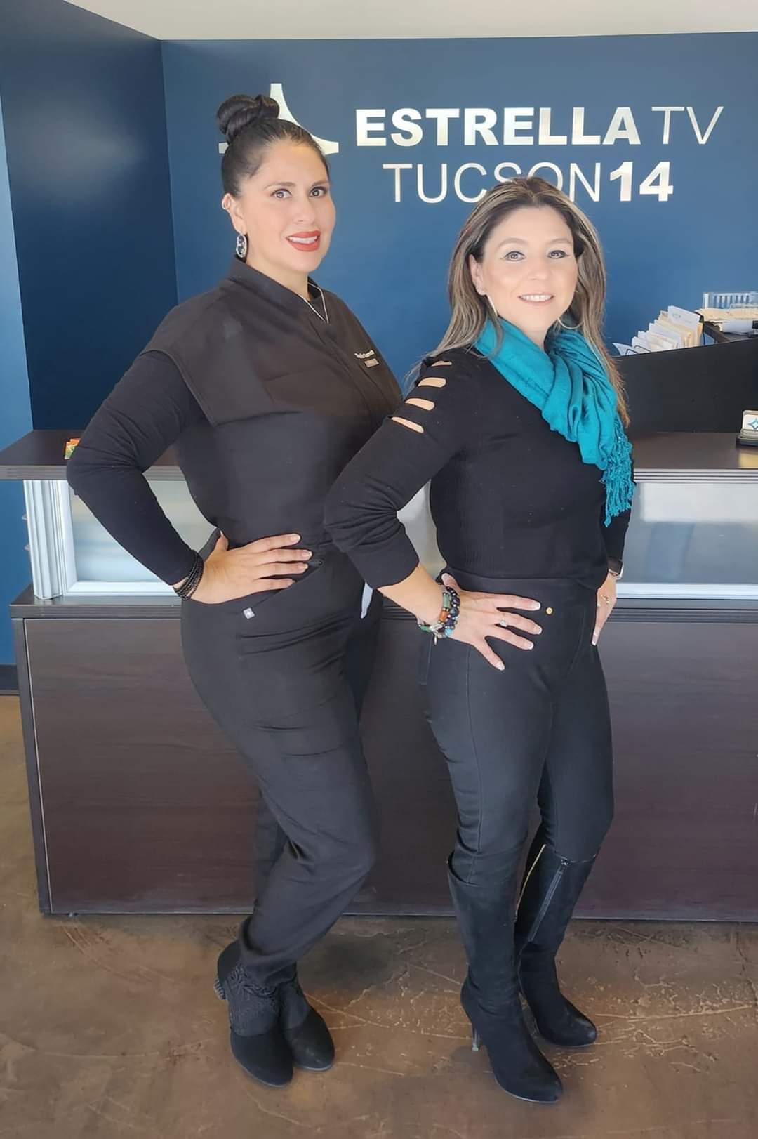 Two women standing next to each other in front of a sign that says estrella tv tucson 14