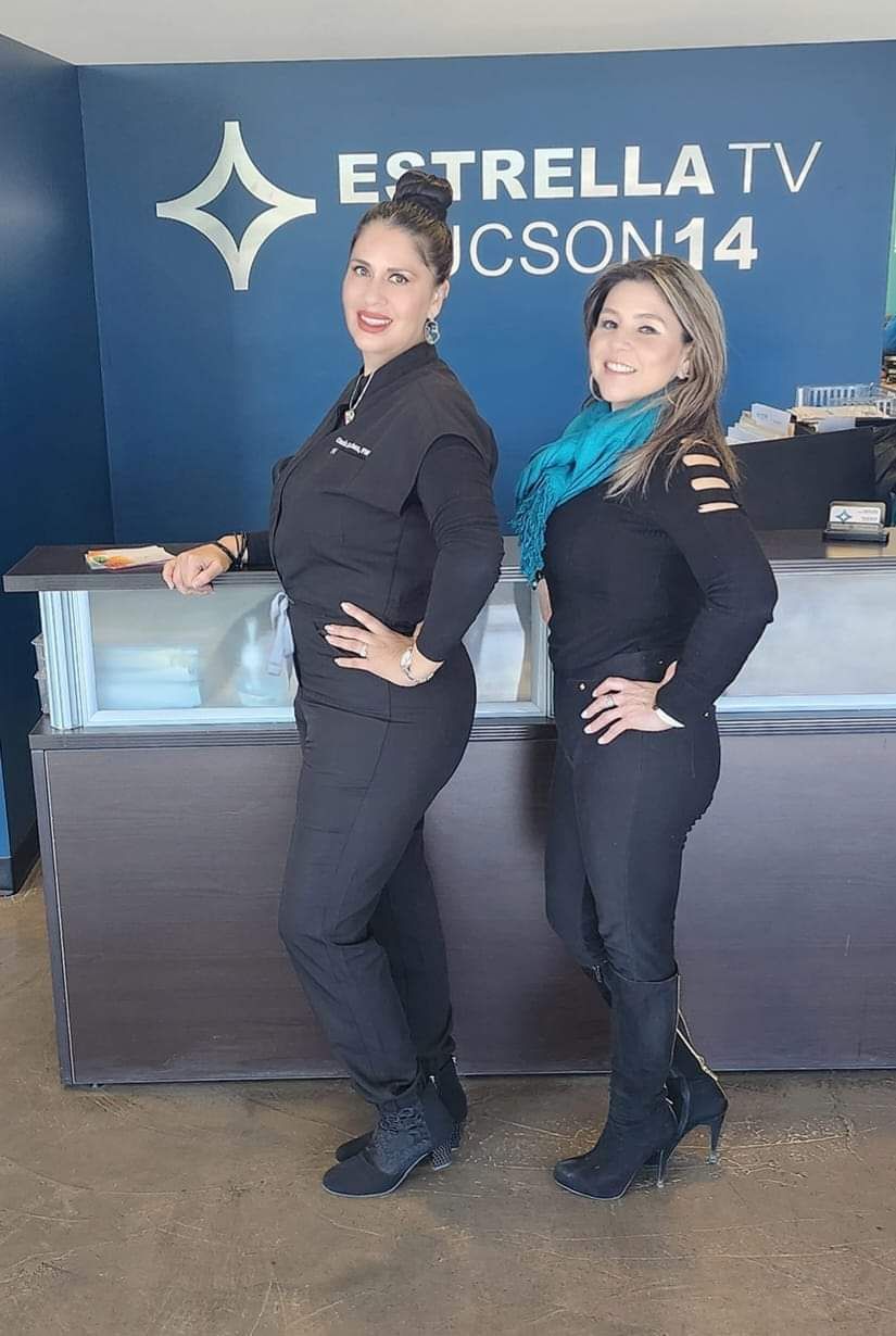 Two women are standing next to each other in front of a counter.