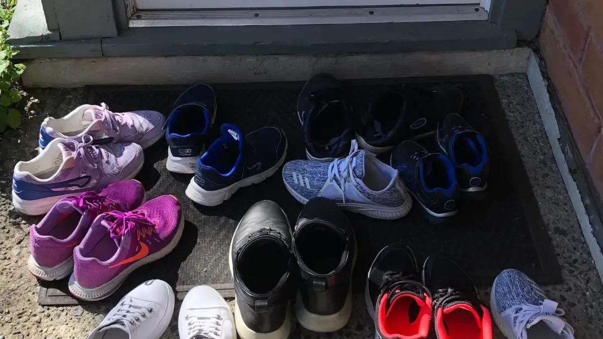 A bunch of shoes are sitting on a mat on the ground.