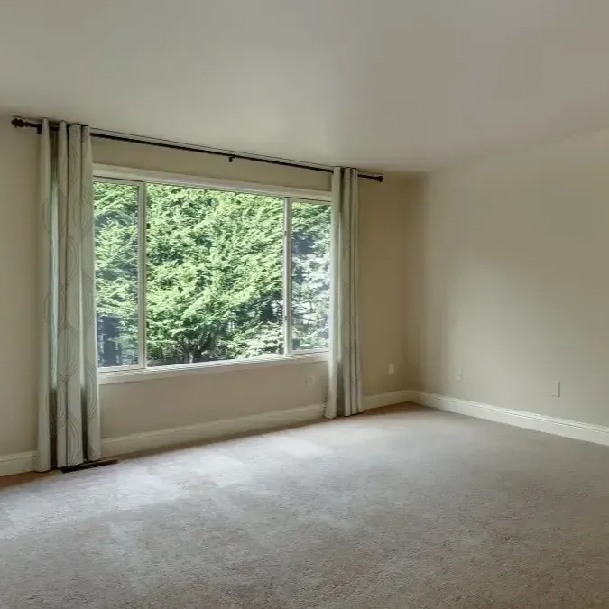 An empty bedroom with a window and a ceiling light.