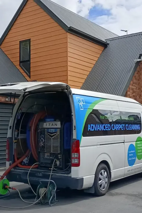 A white van with Advanced Carpet Cleaning equipment parked in front of a house.