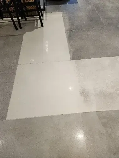Light-colored tiles set on a gray concrete floor; near black chairs.
