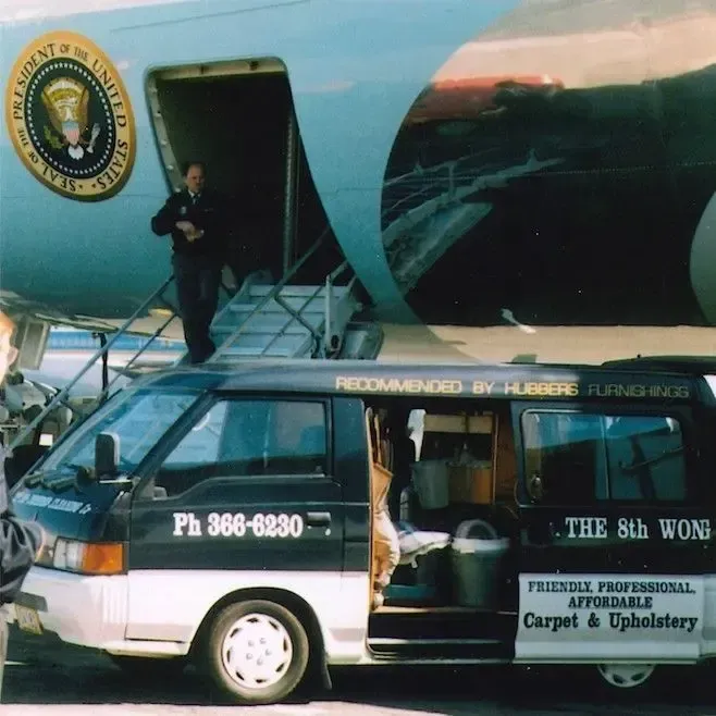 A van that says the 8th Wonder Cleaning is parked in front of an aeroplane