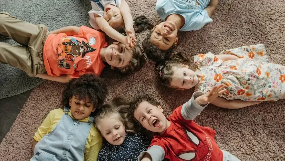 A group of children are laying on the carpet in a circle.