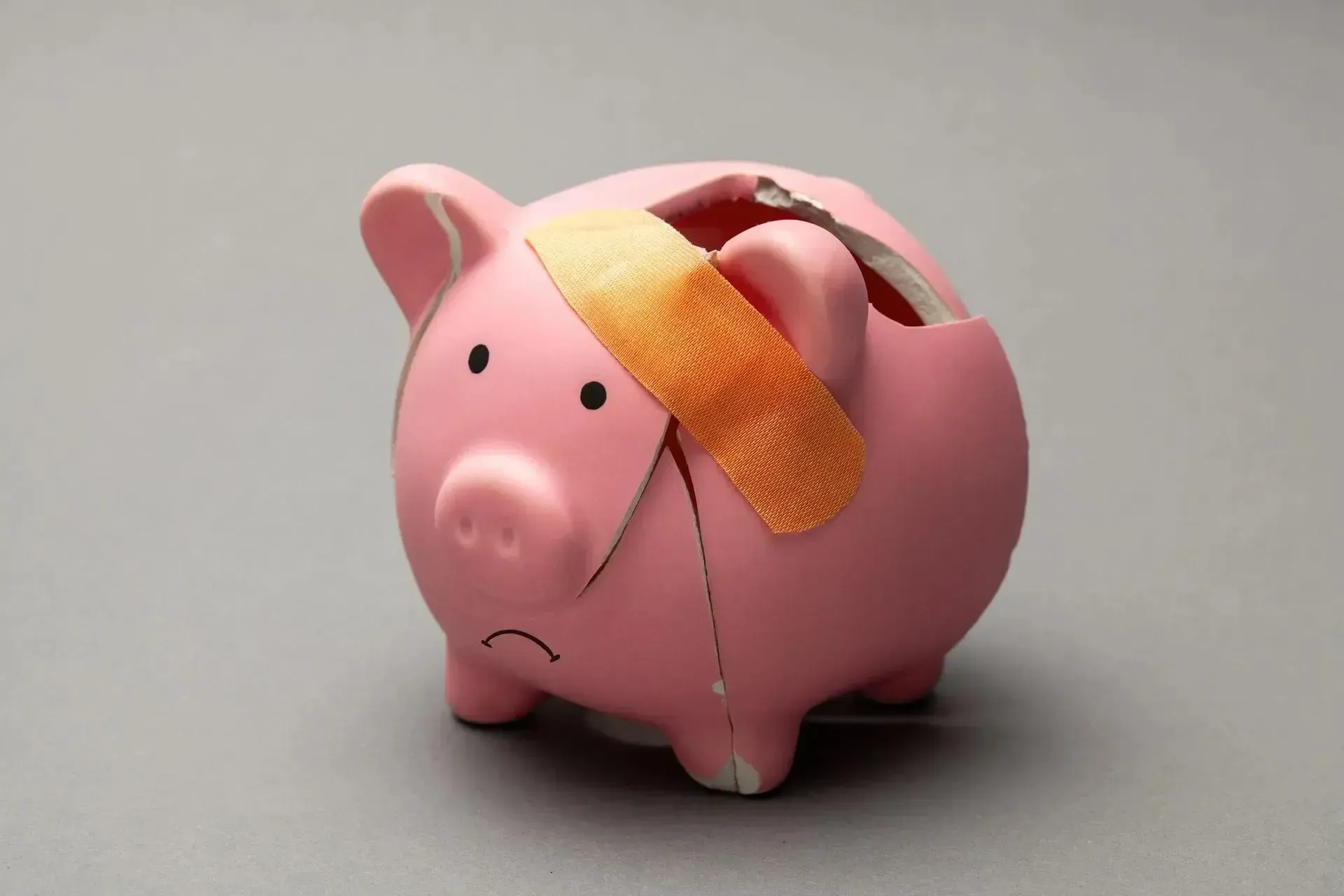 Broken pink piggy bank with bandage.