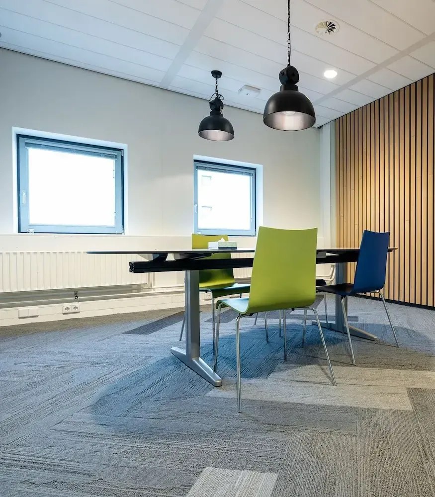 A hallway with a glass wall and a carpeted floor.