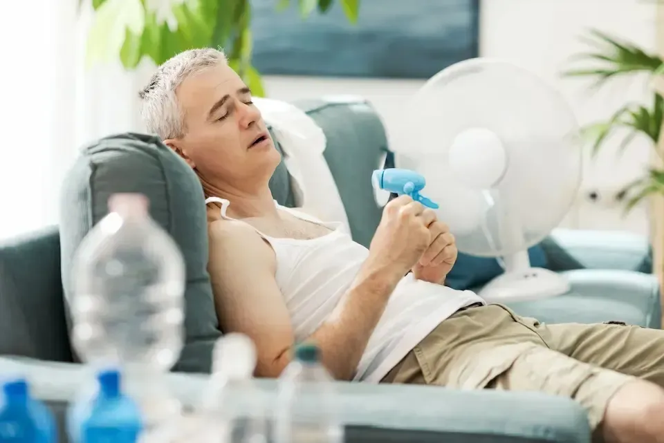 Person resting on a couch and holding a blue inhaler in a bright living room