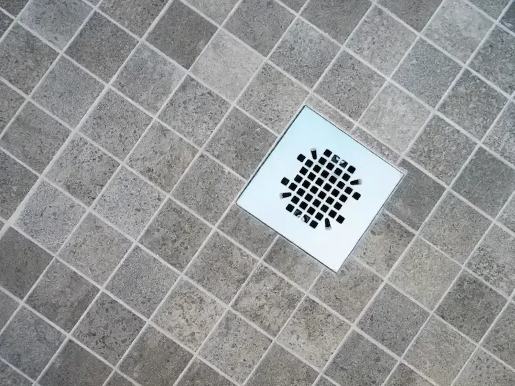 A drain on a tiled floor in a bathroom.