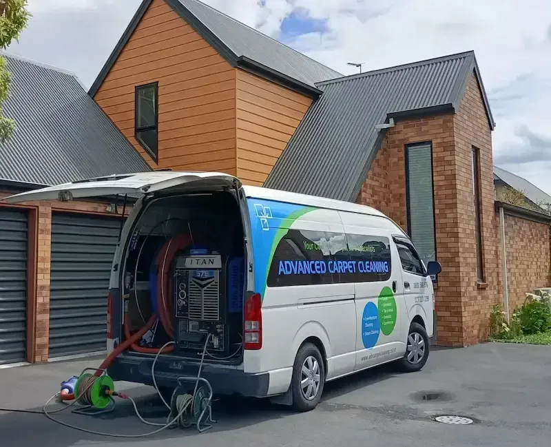 A white van is parked in front of a brick house.