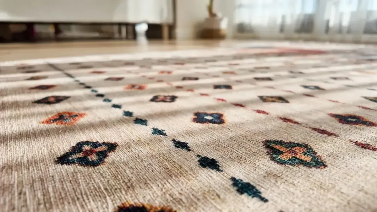 Low-angle view of a patterned beige rug with colorful geometric motifs in a room.