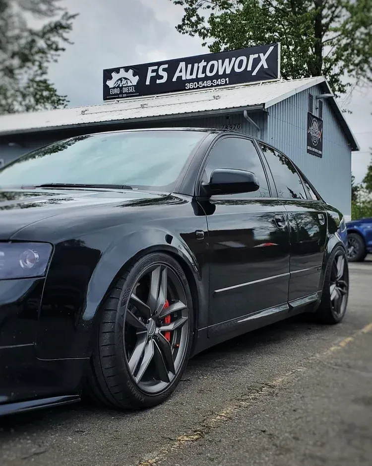 Black lowered sedan parked outside FS Autoworks under cloudy skies.
