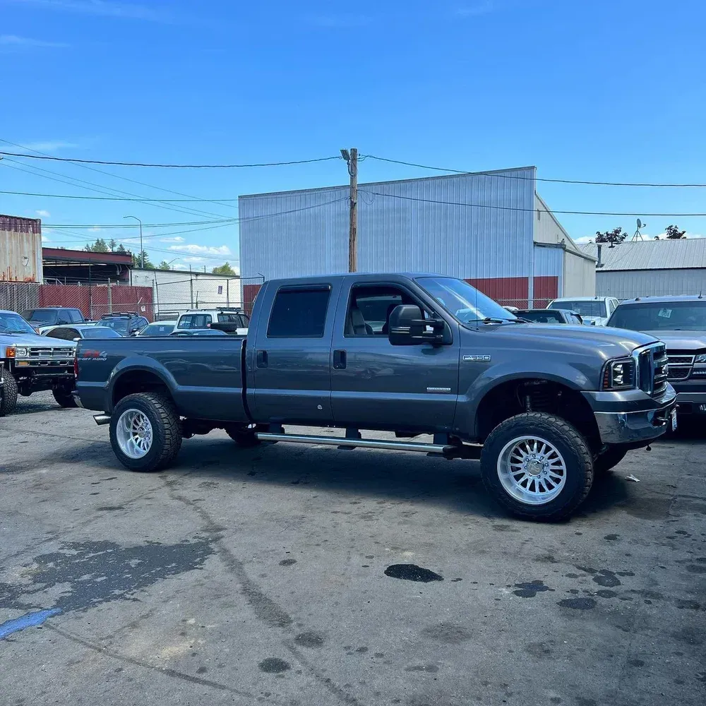 Gray lifted pickup truck parked in an industrial lot under a clear blue sky