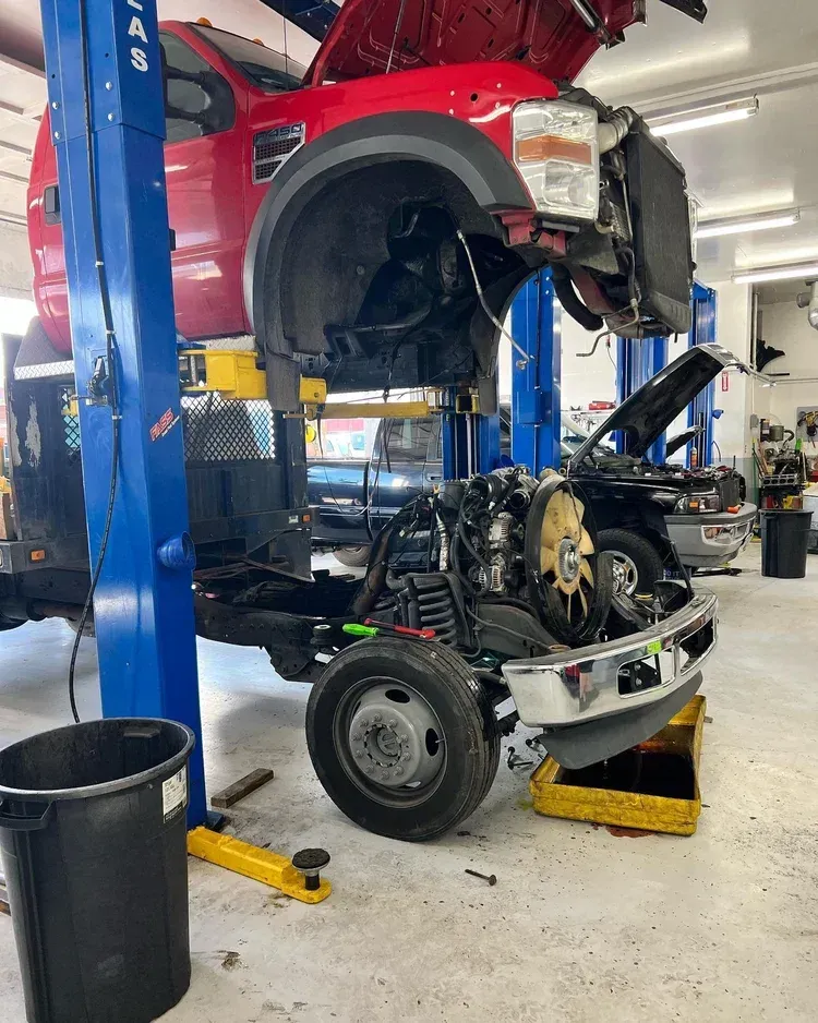 Car lifted in an auto shop, exposing the front end and engine bay during repair