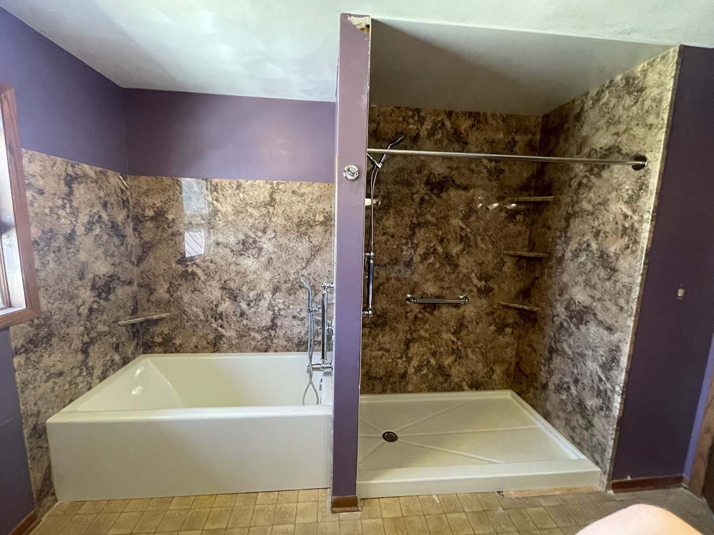 Bathroom with purple walls, brown marbled wall panels. Tub on left, shower on right, divided by a wall.