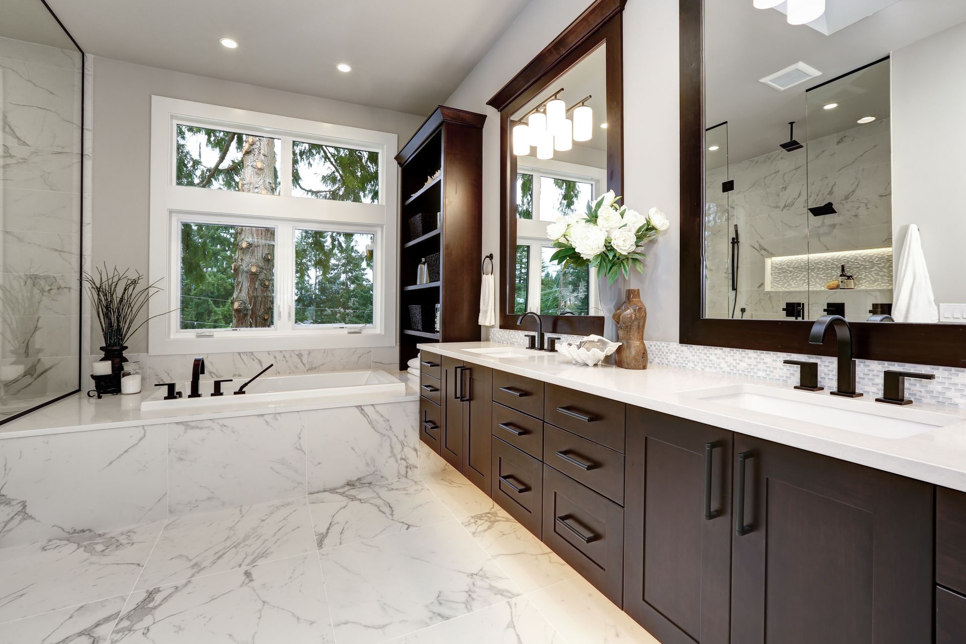 Bathroom with white marble, dark cabinets, a large window, and double sinks. Bathroom with white marble, dark cabinets, a large window, and double sinks.