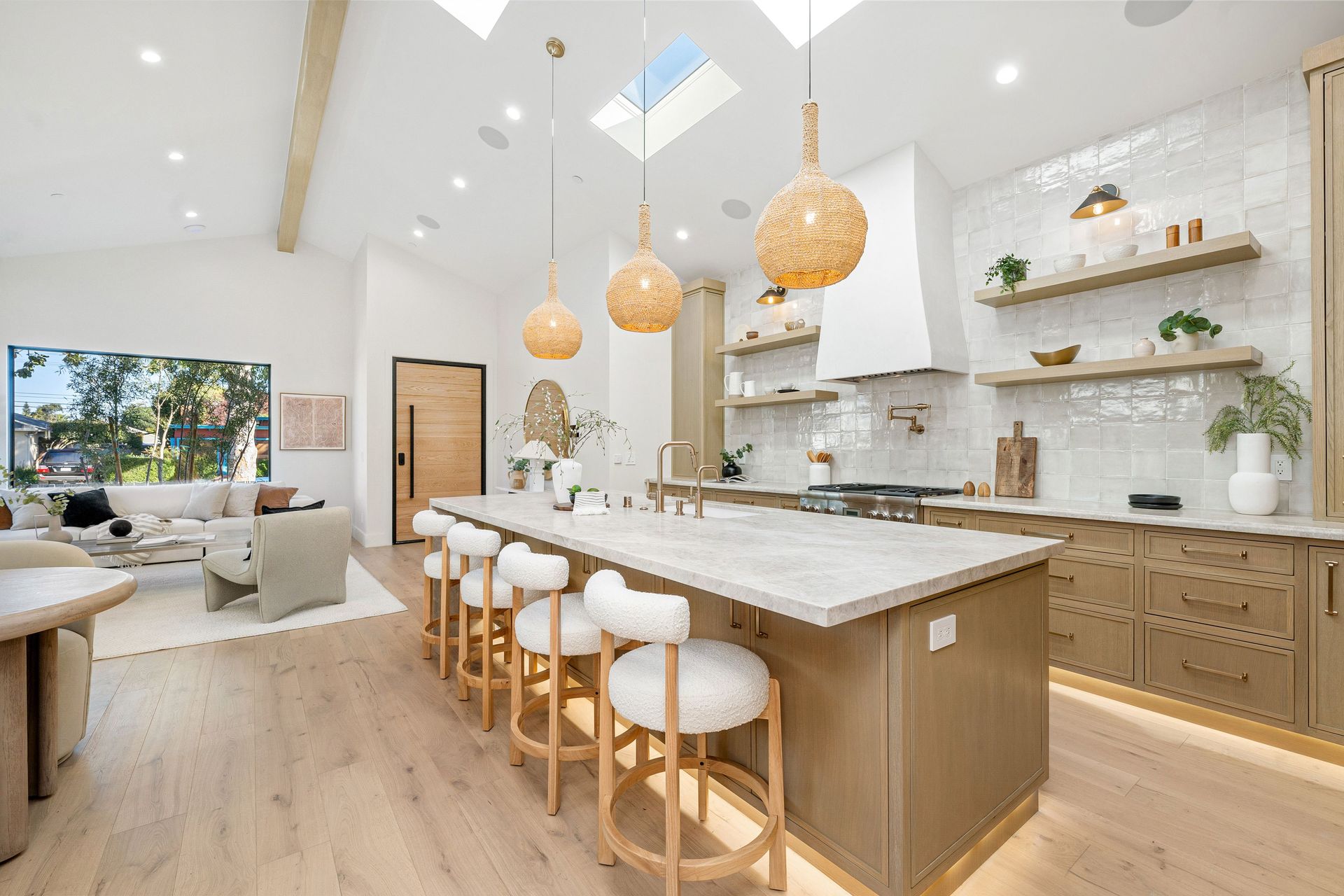 Kitchen with island, light wood cabinets, white countertops, skylight, and pendant lights.