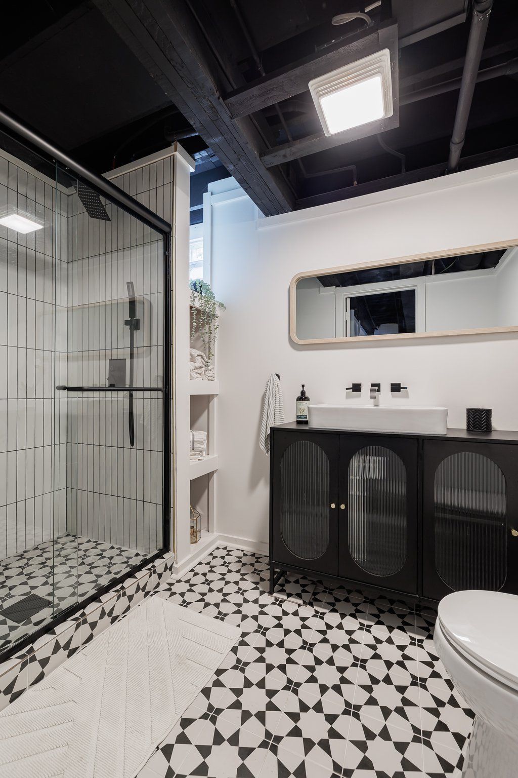 A bathroom with a toilet , sink , shower and mirror.