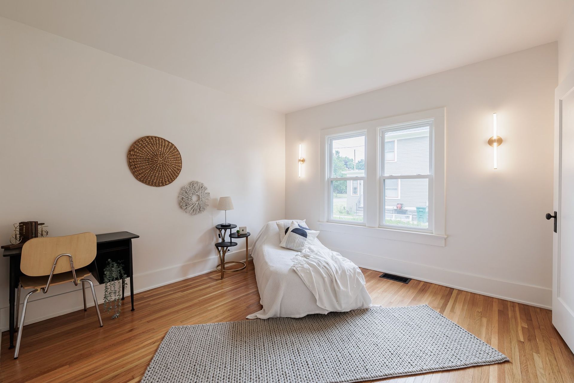 A bedroom with a bed , desk , chair and rug.