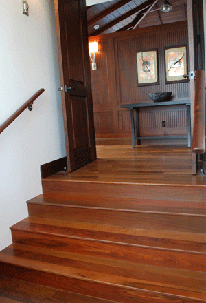 A wooden staircase leading up to a room with a table in the background.