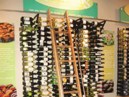 A ladder is going up to a wall of wine bottles