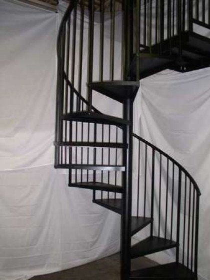 A black spiral staircase with a white curtain behind it