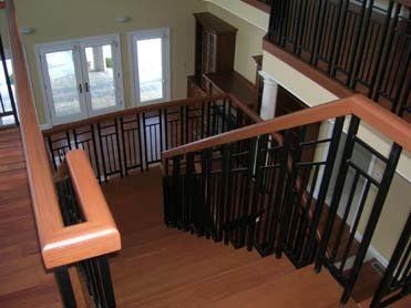 A wooden staircase with a black railing in a house.