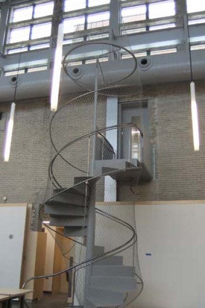 A spiral staircase in a building with lights hanging from the ceiling