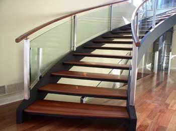 A curved staircase with wooden steps and a glass railing