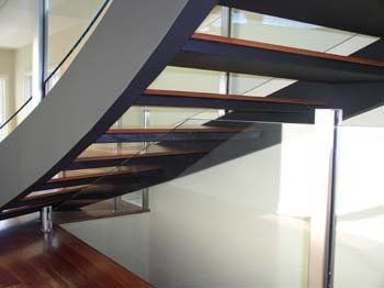 curved wood staircase with glass rail