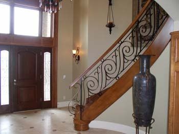 A wooden staircase with a wrought iron railing in a hallway.