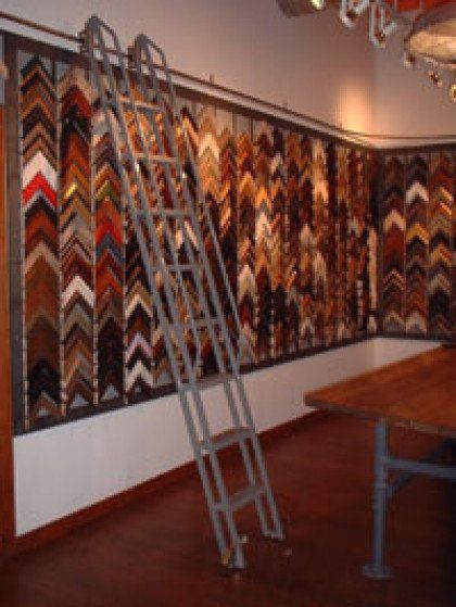 A ladder is in front of a wall of picture frames