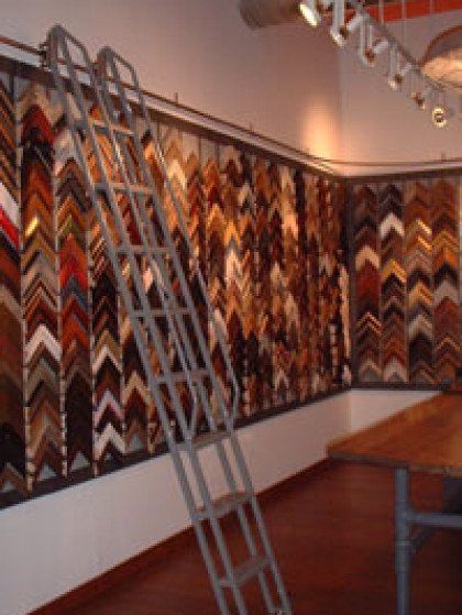 A ladder is in front of a wall of picture frames