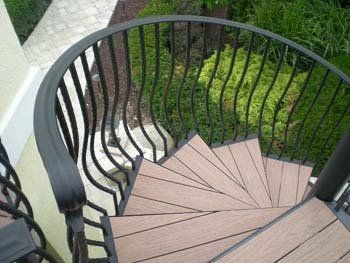 A spiral staircase with wooden steps and a wrought iron railing.