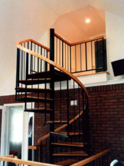 A spiral staircase with wooden steps and a black railing