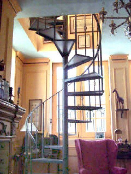 A living room with a spiral staircase and a pink chair