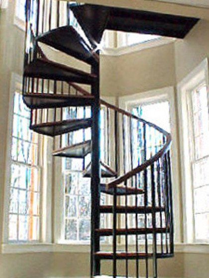 A spiral staircase in a room with lots of windows