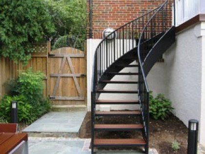 A spiral staircase is leading up to a wooden gate.