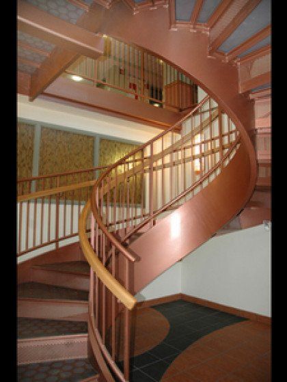 A copper spiral staircase with a wooden railing