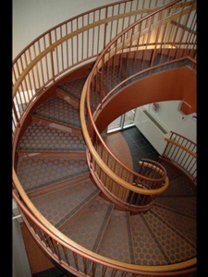 A close up of a spiral staircase with a wooden railing