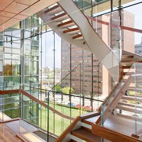 A staircase in a building with lots of windows and a view of the city.
